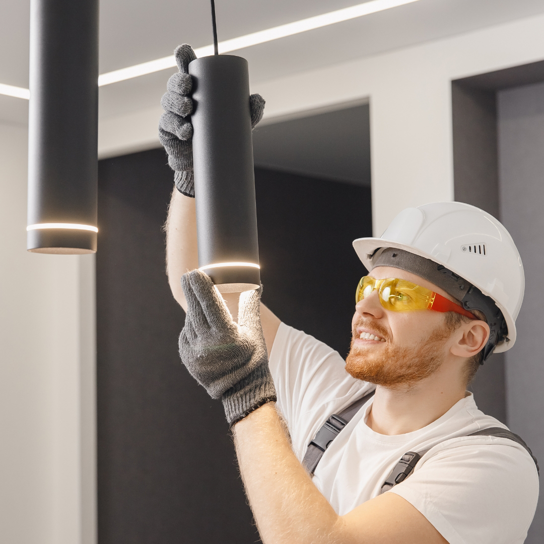 A local electrician installs a light fixture in a home.